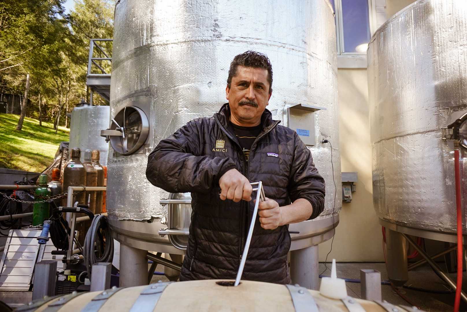 Olema winery crew member stirring a barrel of wine