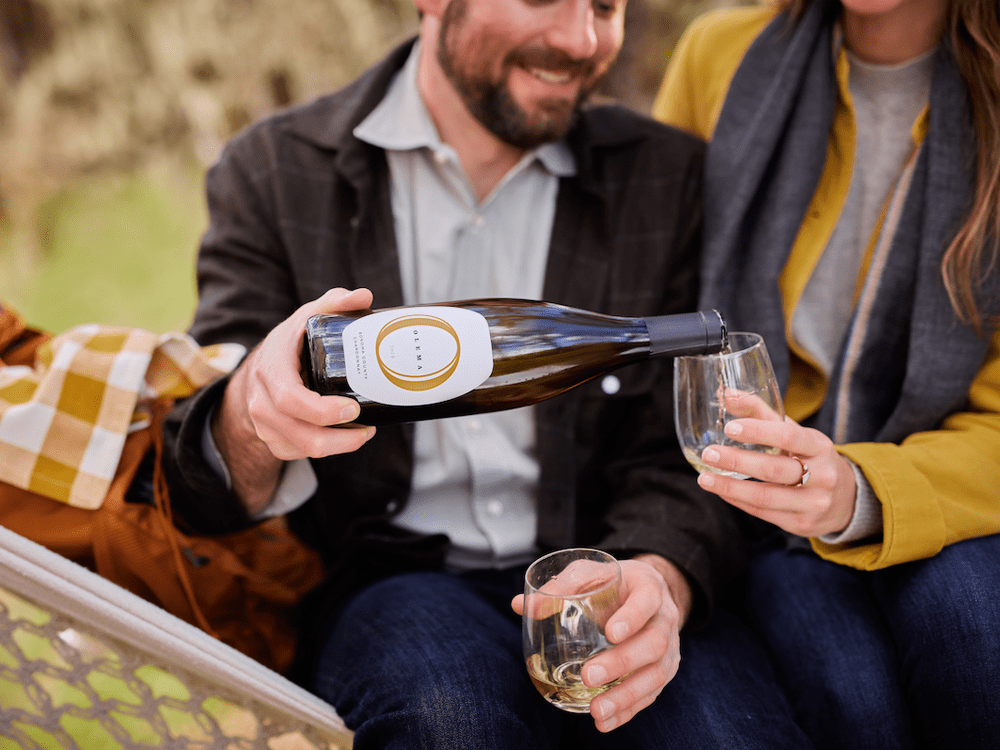 Man pouring chardonnay into woman's wine glass